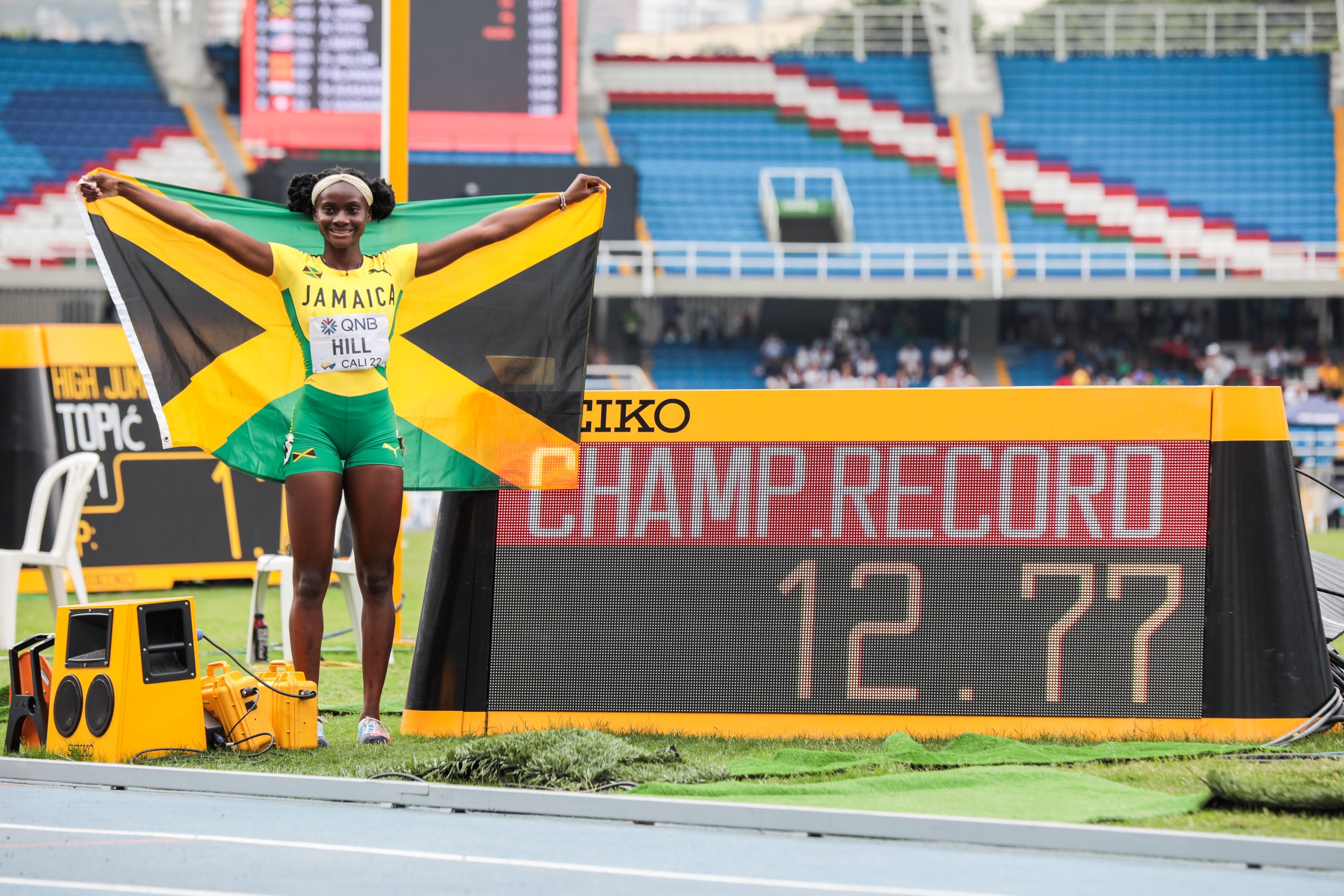 Kerrica Hill poses at the clock to celebrate her 12.77 championship record on Saturday's (6 Aug) final day of the Cali22 World Athletics U20 Championships in Colombia.